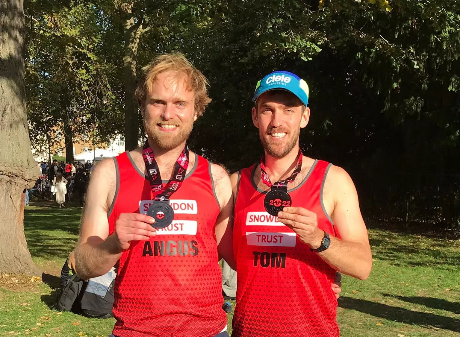 Image of two Snowdon Trust marathon runners smiling and posing for the camera holding their marathon medals