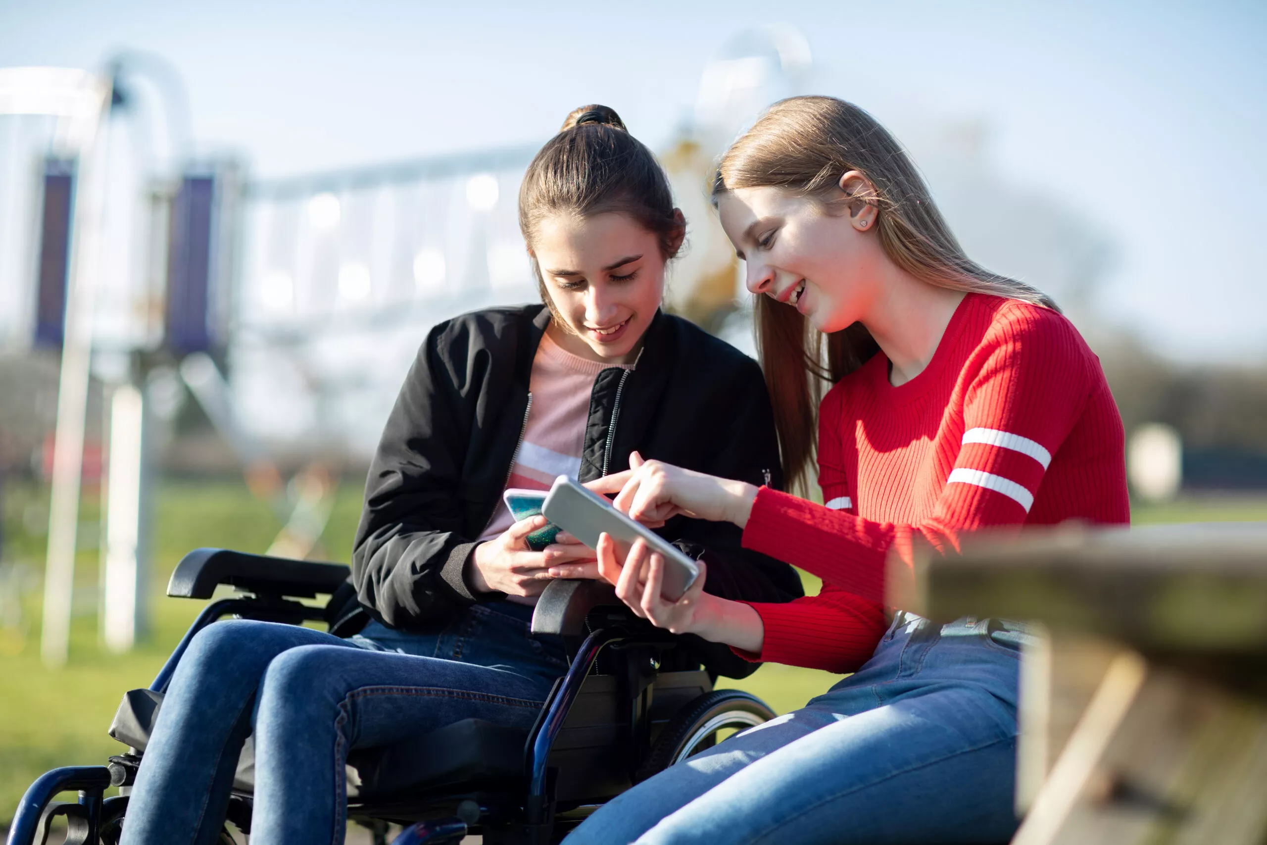 Image of two girls looking on their phones and talking to each other